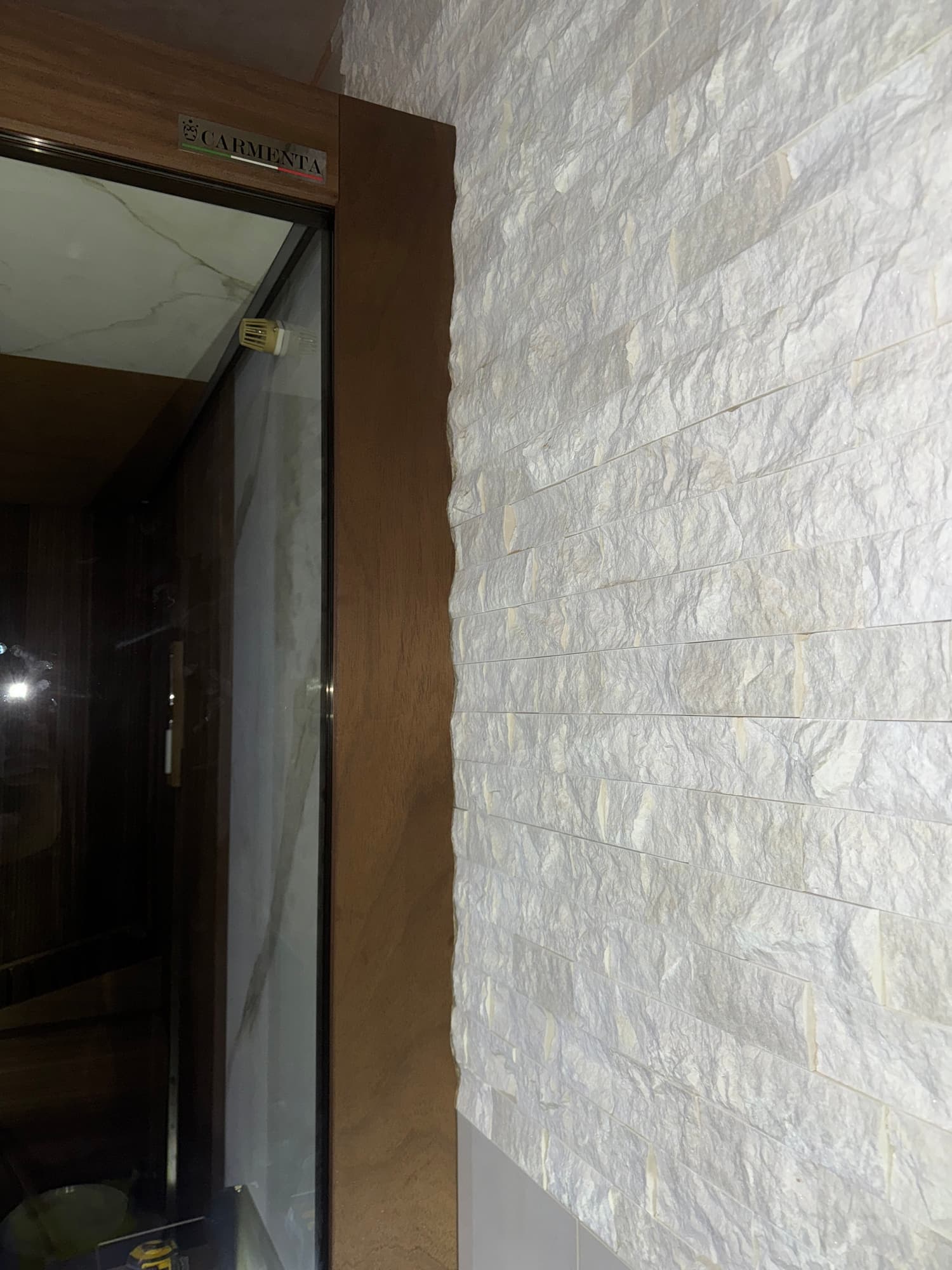 Detail of the scribed sauna door surround beside the textured stone wall