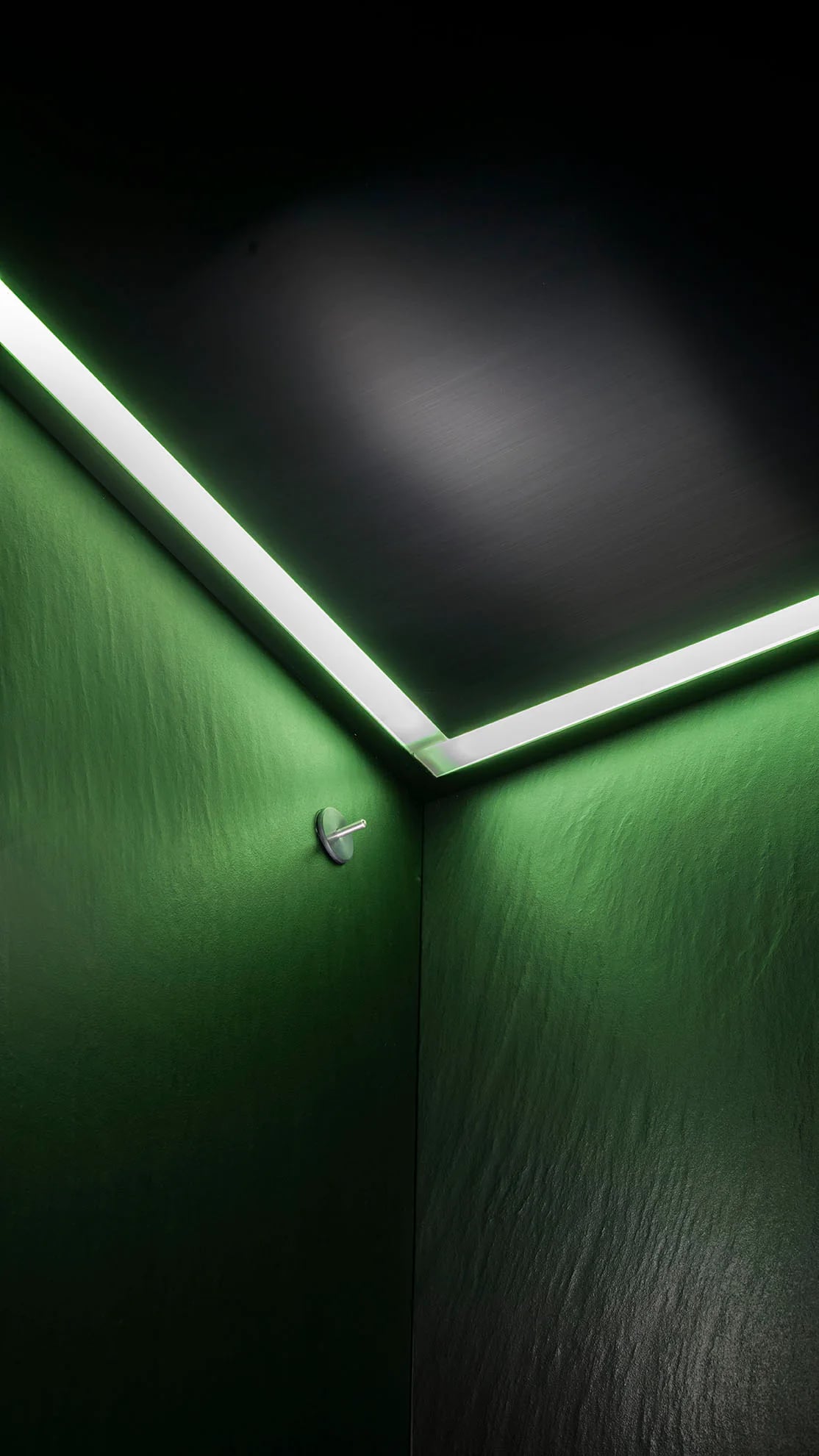 Green chromotherapy lighting across a ribbed steam room wall