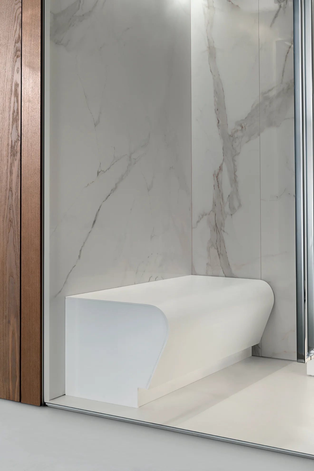 Marble-effect wall finish and curved bench seen through a glass doorway