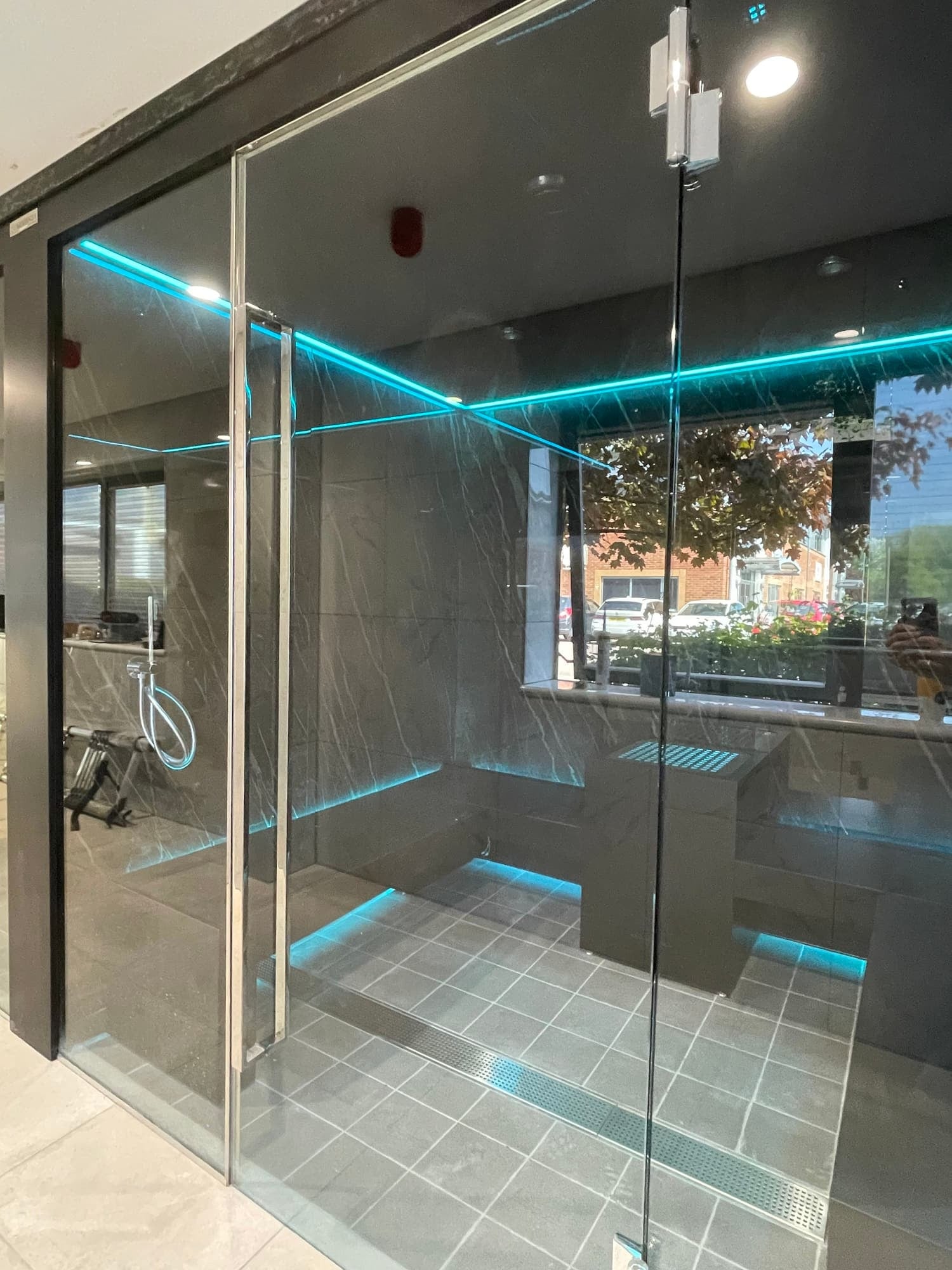 Glass-fronted professional steam room with teal perimeter lighting